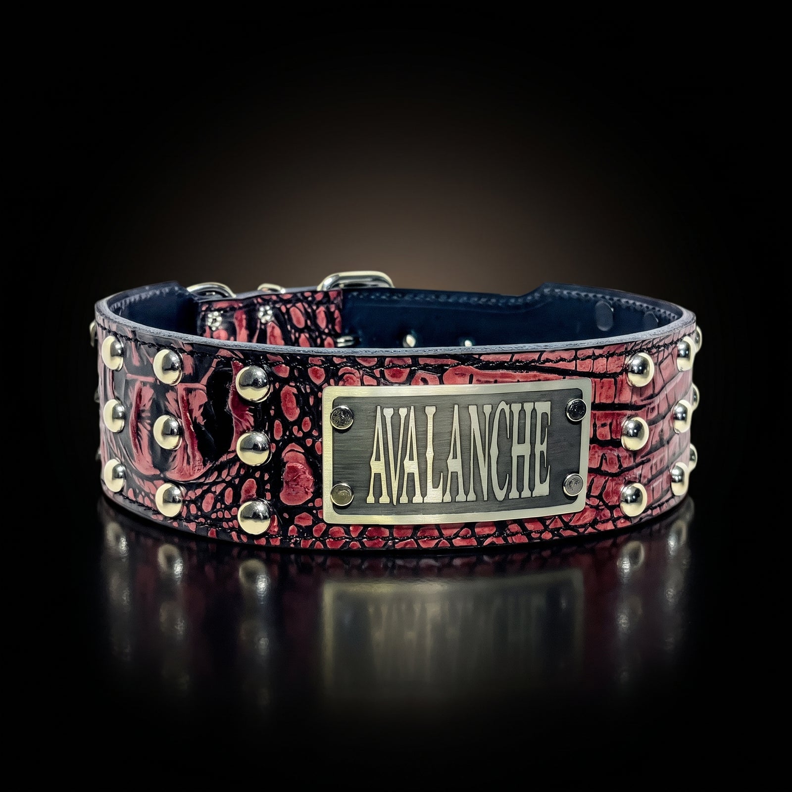 A red and black crocodile-embossed leather dog collar with silver studs and a central silver metal plate engraved with the name 'AVALANCHE'.
