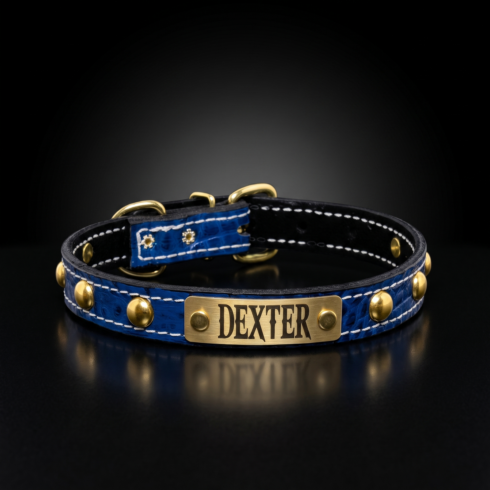 A personalized blue crocodile-embossed leather dog collar with gold-tone hardware, white stitching, and a brass nameplate engraved with the name 'DEXTER'.