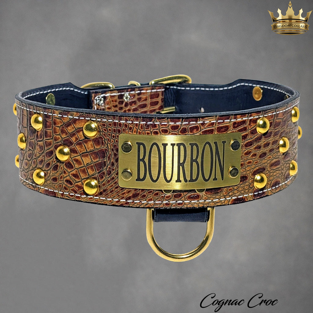 Brown leather dog collar with gold studs and 'Bourbon' plaque on a gray background