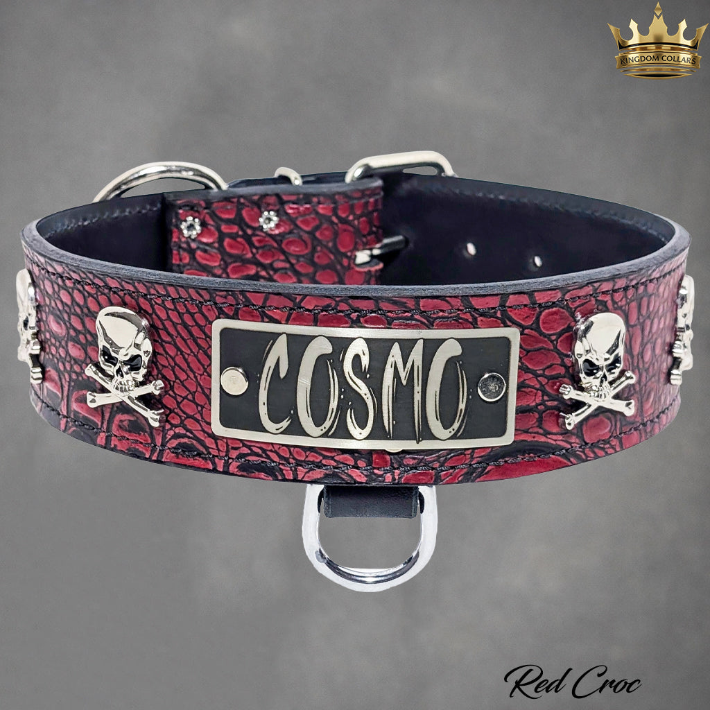 Dog collar with red crocodile pattern and 'Cosmo' nameplate on a gray background