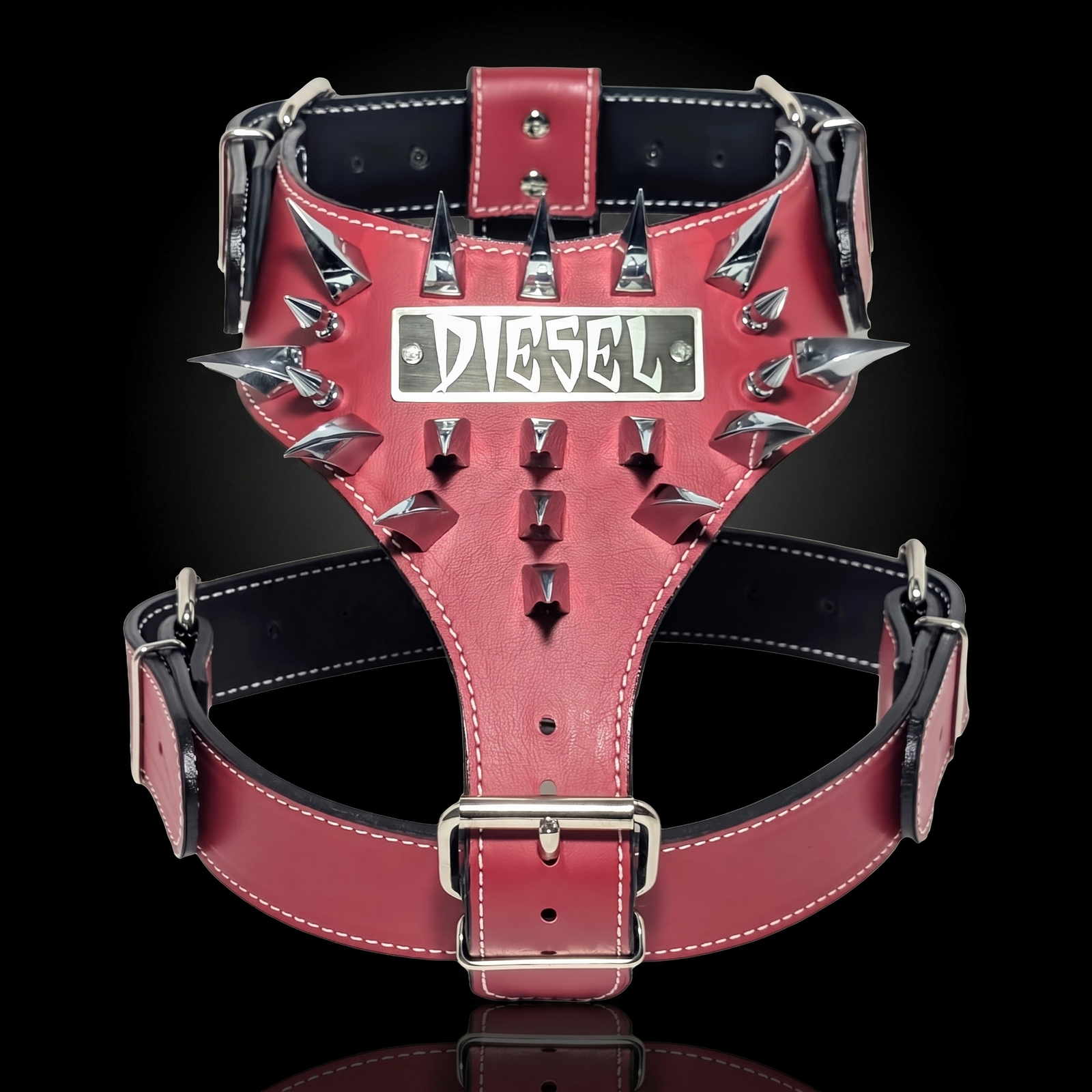 A red leather dog harness with silver metal spikes and a central silver plate featuring the Diesel logo, set against a solid black background.