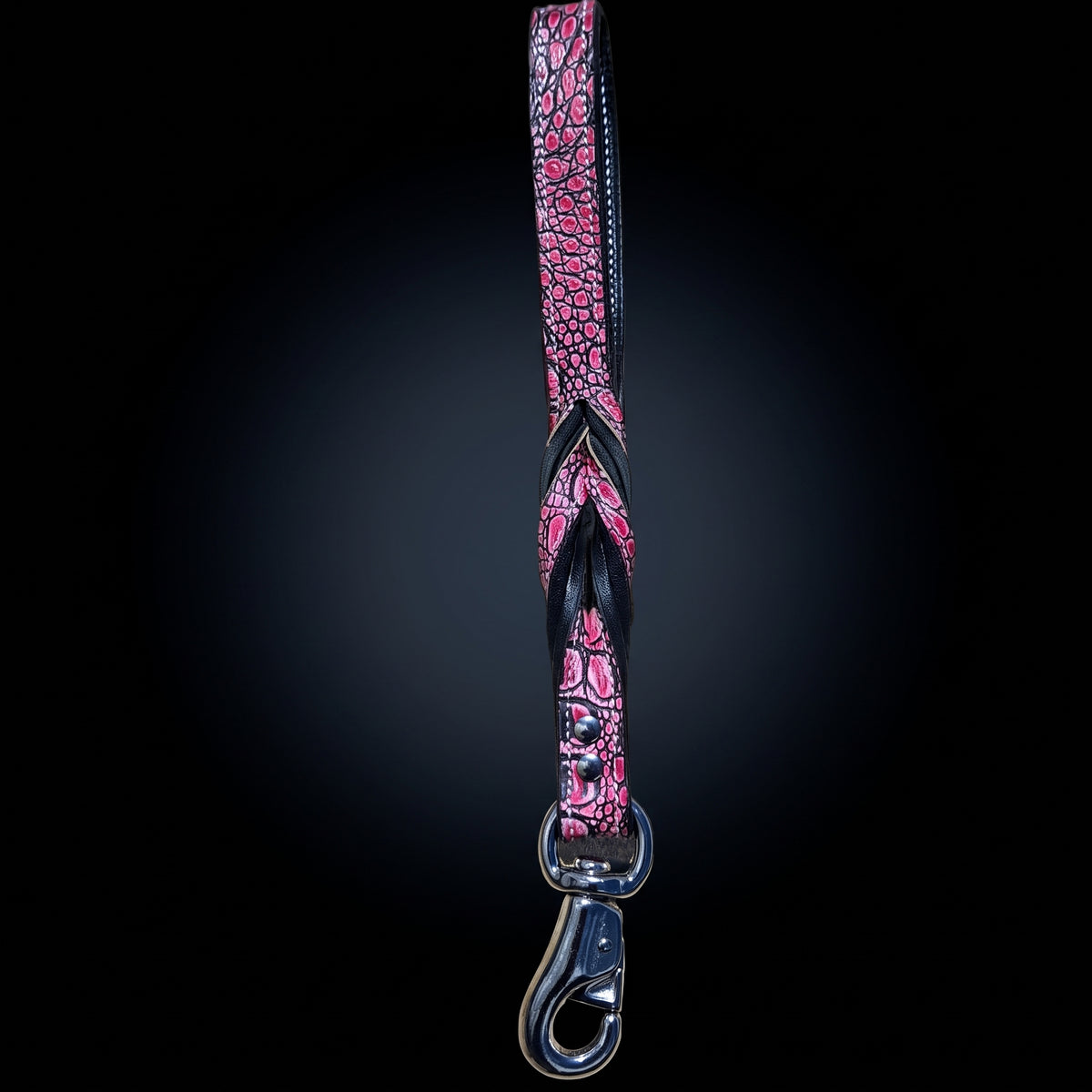 A pink and black crocodile-embossed strap with a silver metal swivel clasp, shown vertically against a dark gradient background.