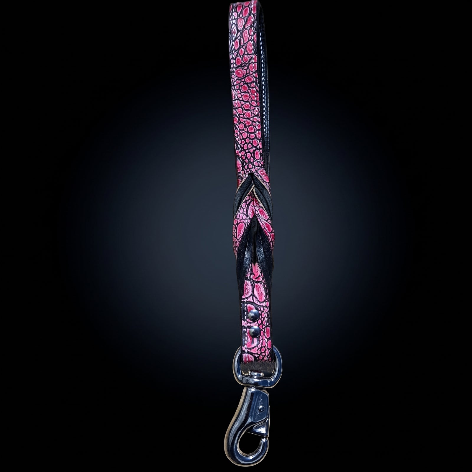 A pink and black crocodile-embossed strap with a silver metal swivel clasp, shown vertically against a dark gradient background.