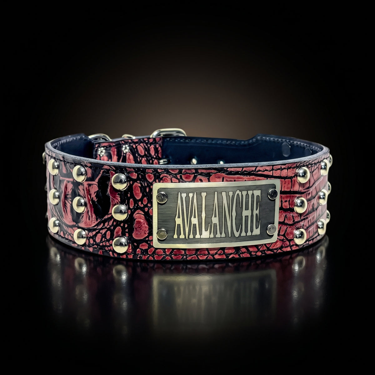 A red and black crocodile-embossed leather dog collar with silver studs and a central silver metal plate engraved with the name 'AVALANCHE'.