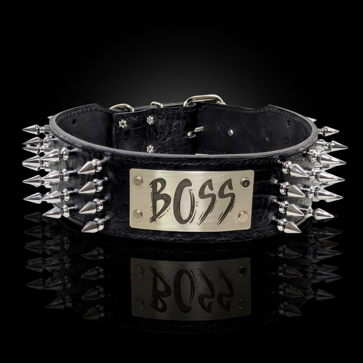 A black leather studded collar with a silver-tone metal plate engraved with the word 'BOSS', photographed on a reflective black background.