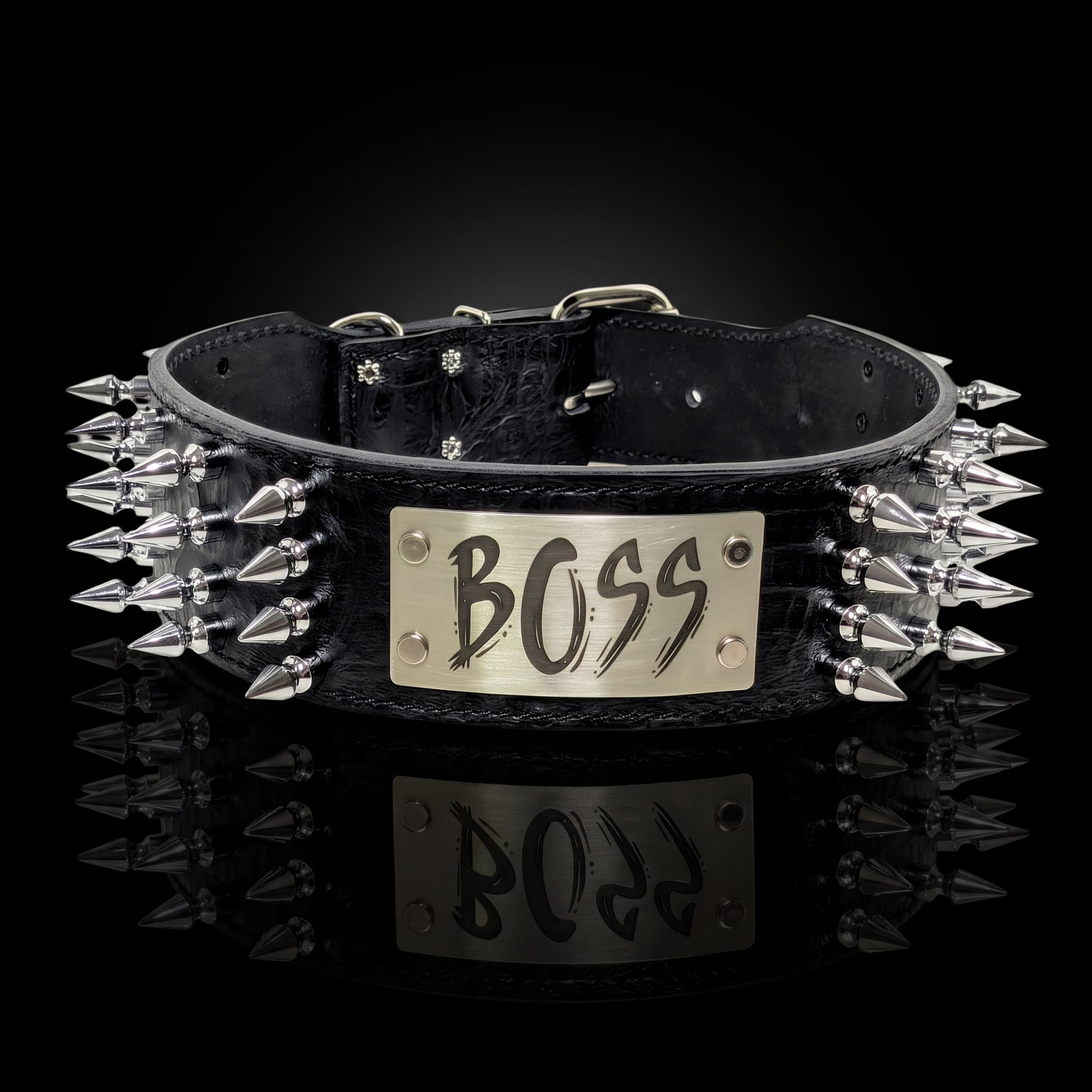 A black leather studded collar with a silver-tone metal plate engraved with the word 'BOSS', photographed on a reflective black background.