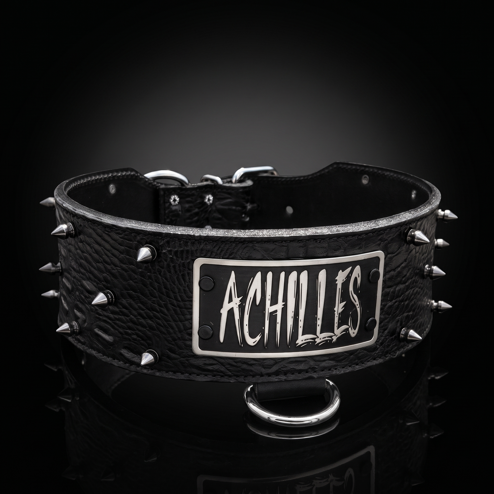 A black textured leather dog collar with silver metal spikes and a central silver plate engraved with the name 'ACHILLES' in a stylized font, shown on a reflective black background.