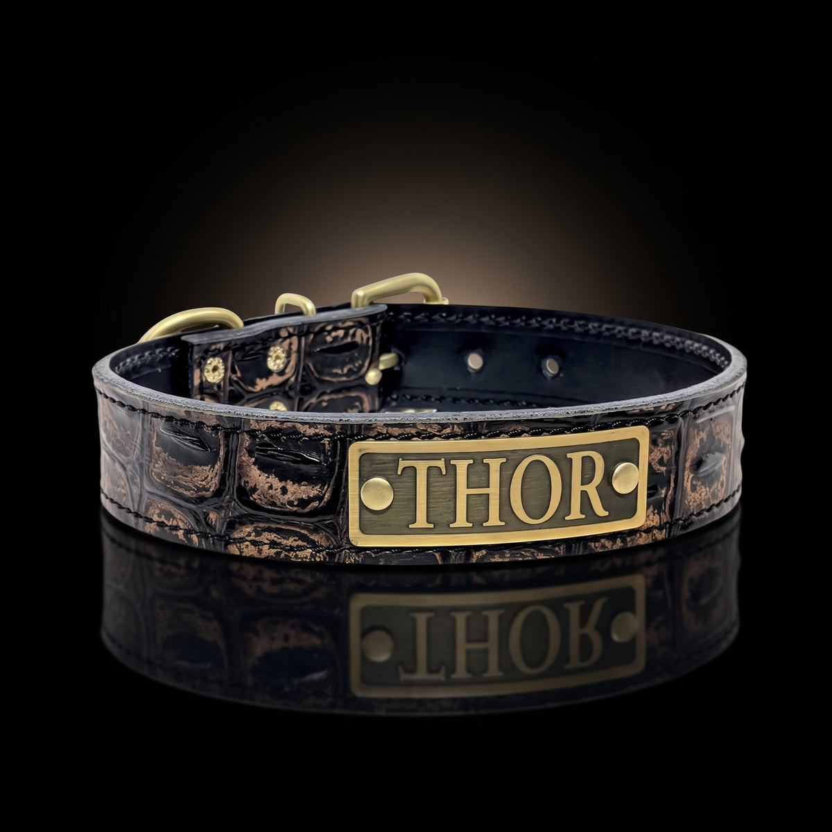 A 1.5-inch wide crocodile-embossed Italian leather collar featuring heavy-duty brass hardware and a custom engraved metal ID plate.