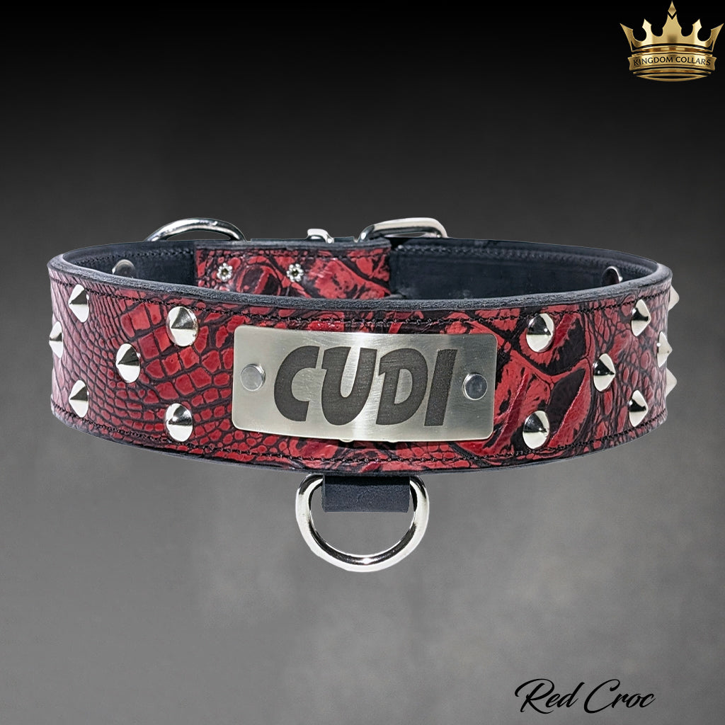 A red crocodile-embossed leather dog collar with silver studs and a central silver metal plate engraved with 'CUDI'.