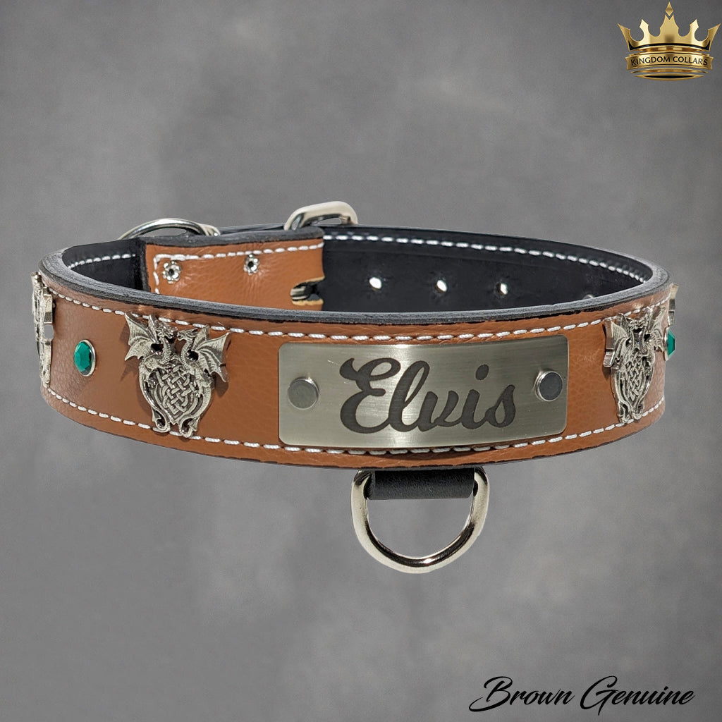 A brown leather dog collar with silver metal hardware, featuring a central silver plate engraved with the name 'Elvis', decorative metal lion head emblems on the sides, and small green gem accents. The collar is displayed against a textured gray background with a gold crown logo in the top right corner and 'Brown Genuine' text in the bottom right corner.
