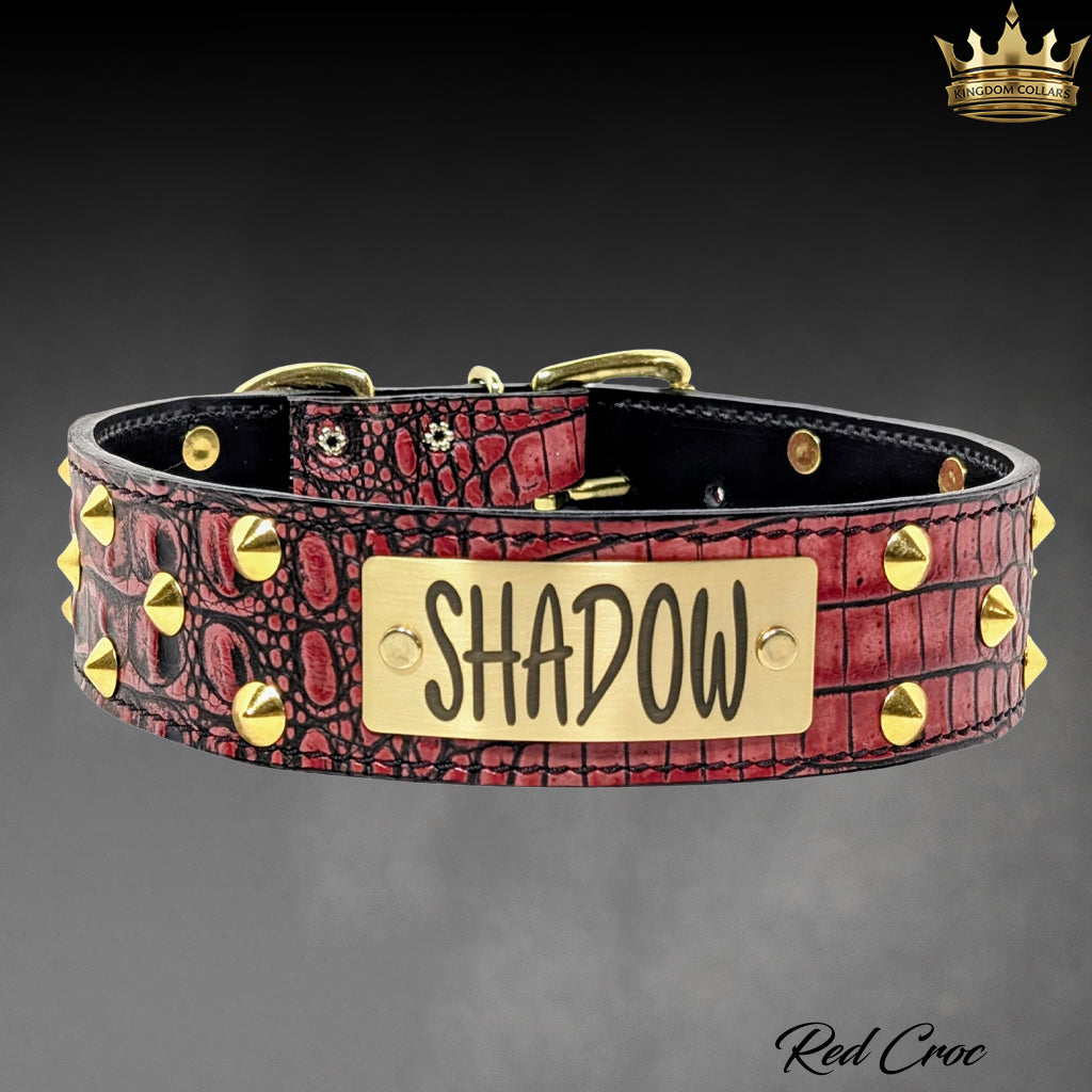 A red crocodile-embossed leather collar with gold-tone studs and a central gold metal plate engraved with the name 'SHADOW'.