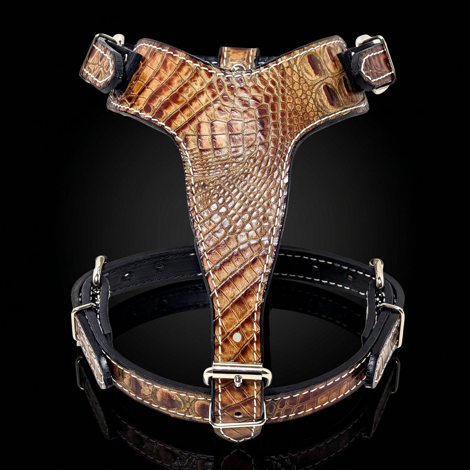 Brown crocodile-embossed leather dog harness with silver hardware, shown on a reflective black background.
