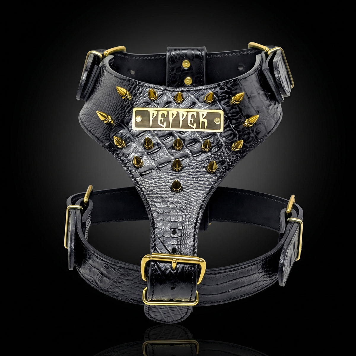 Black crocodile-embossed dog harness with gold hardware and a central nameplate reading 'PEPPER', shown on a black background.
