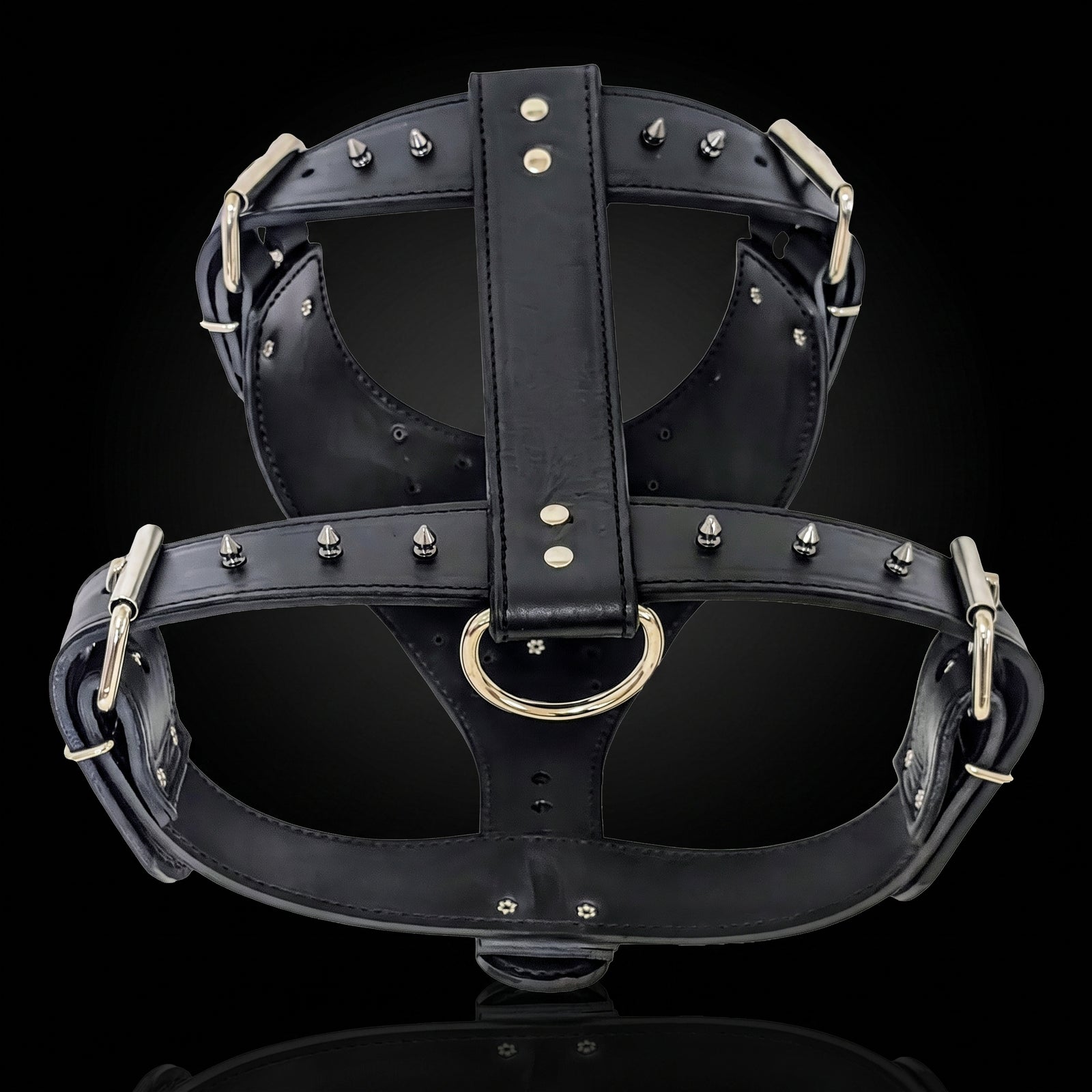 Black leather harness with silver-tone metal studs, buckles, and a central D-ring, shown on a black background.