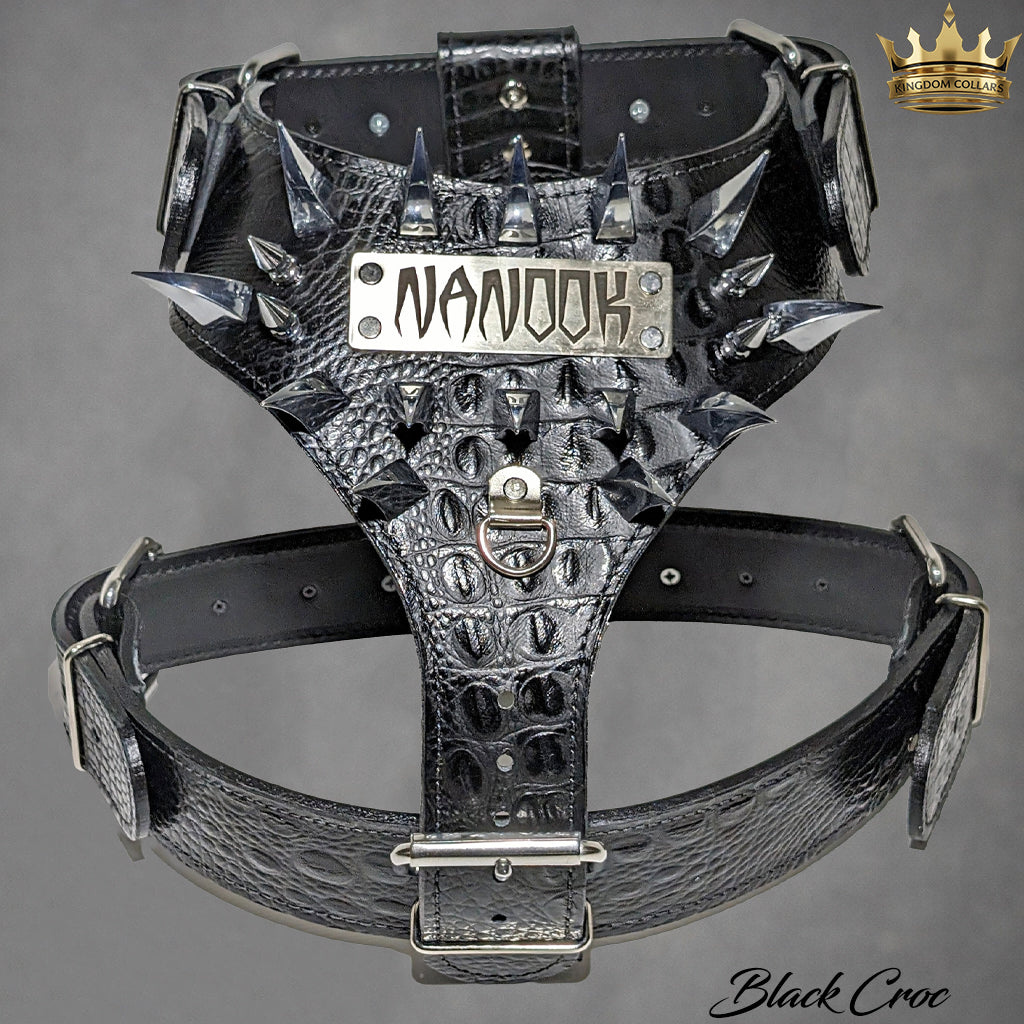A black crocodile-embossed leather dog harness with silver spikes, buckles, and hardware, featuring a central metal plate engraved with the word 'NANOOK'.