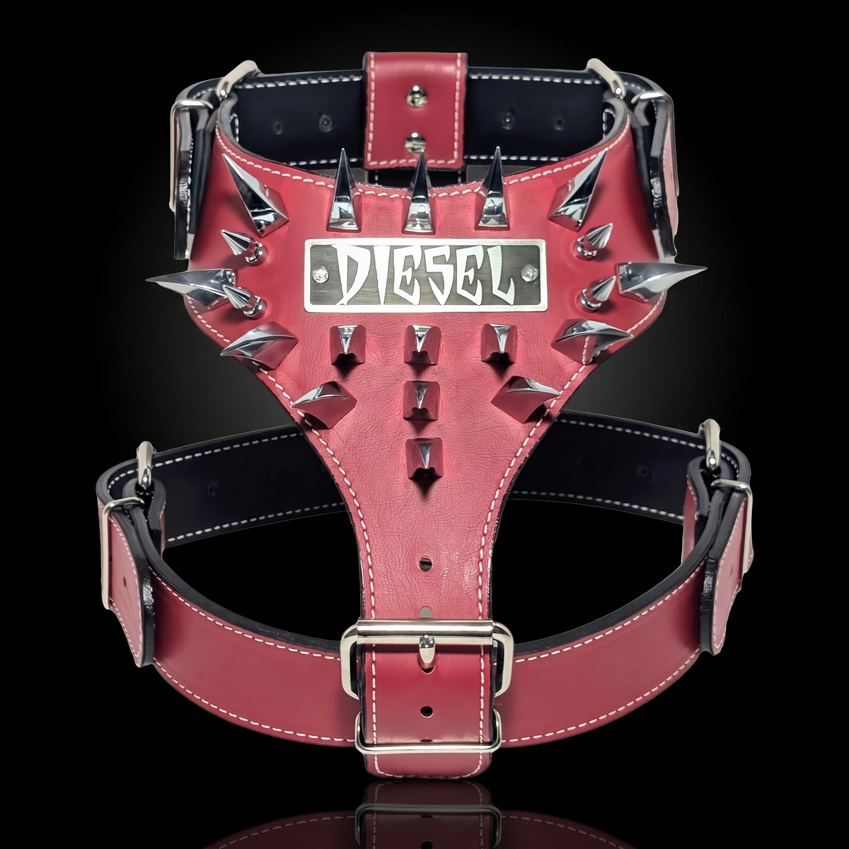 A red leather dog harness with silver metal spikes and a central silver plate featuring the Diesel logo, set against a solid black background.