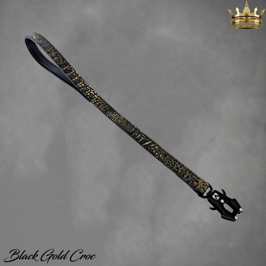 Black and gold crocodile patterned belt on a gray background