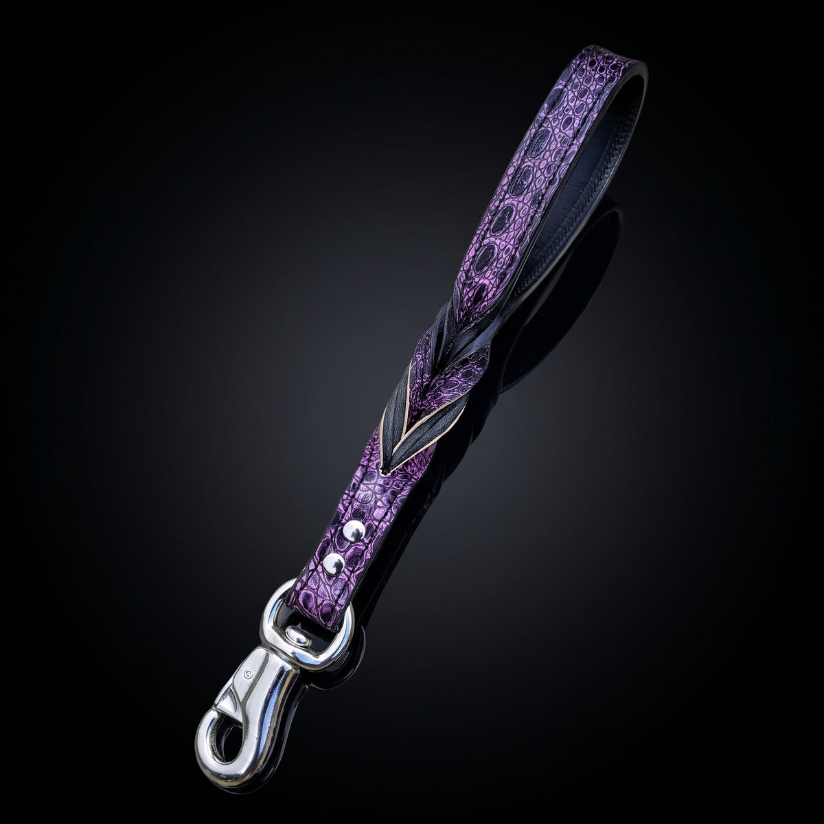 A purple textured leather dog leash with a silver-tone metal clasp, shown on a dark reflective background.