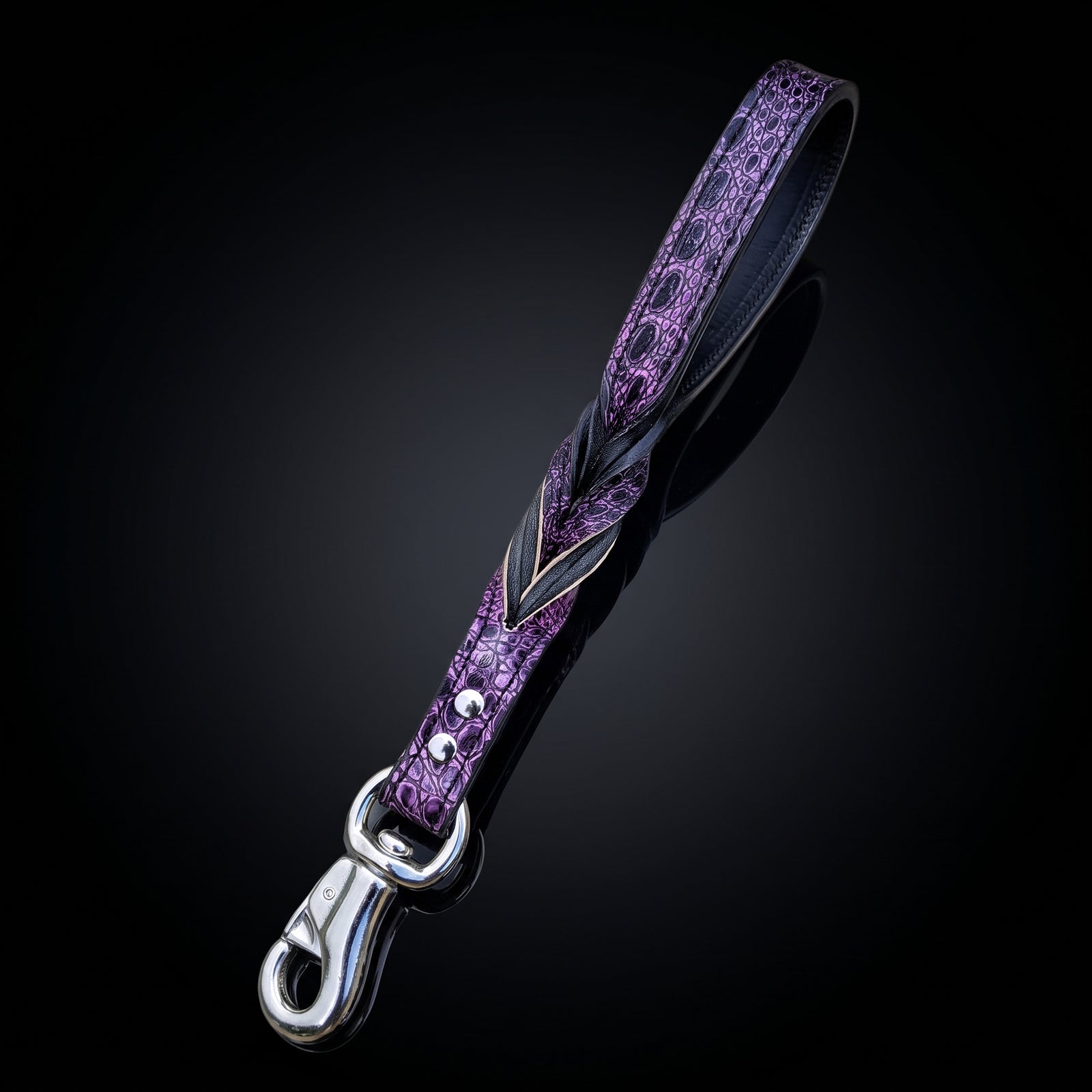 A purple textured leather dog leash with a silver-tone metal clasp, shown on a dark reflective background.