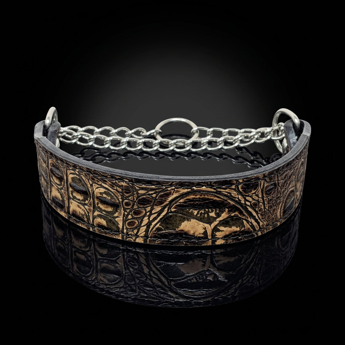 A wide leather cuff bracelet with embossed animal print and a silver chain link accent, displayed on a reflective black surface against a dark background.
