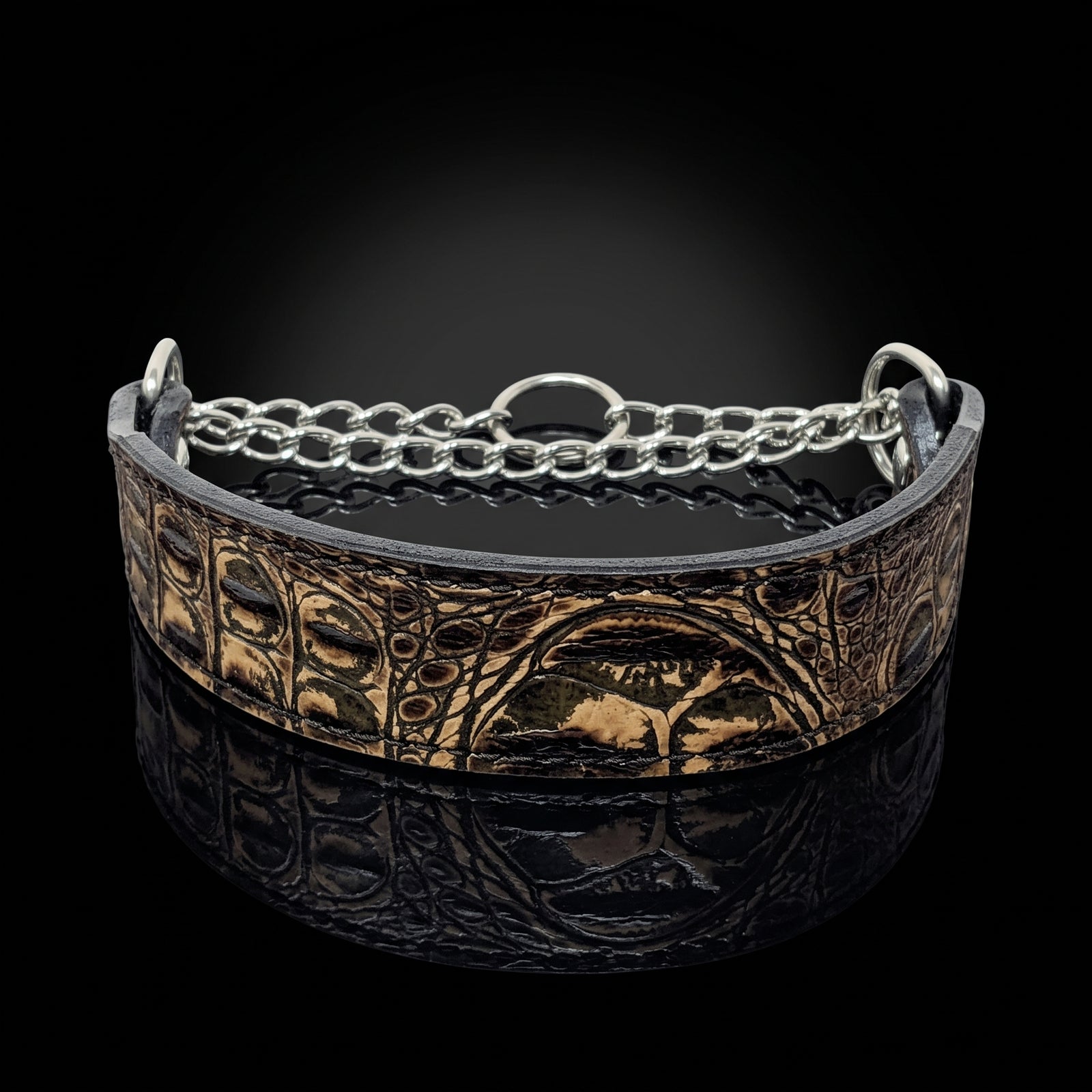 A wide leather cuff bracelet with embossed animal print and a silver chain link accent, displayed on a reflective black surface against a dark background.