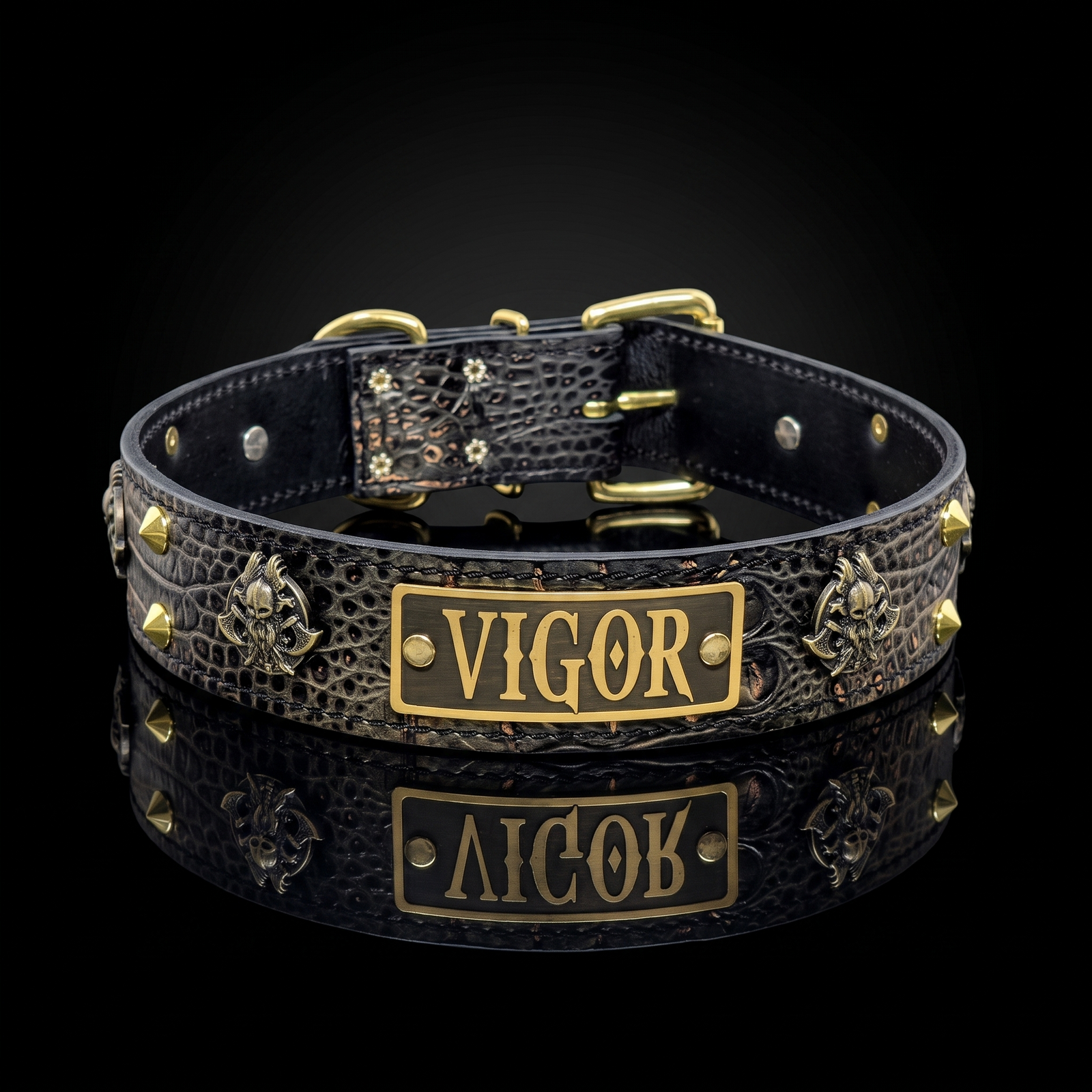 A black crocodile-embossed leather collar with gold-tone hardware, featuring a central rectangular gold plate engraved with the name 'VIGOR' and decorative gold studs and medallions, shown on a reflective black background.